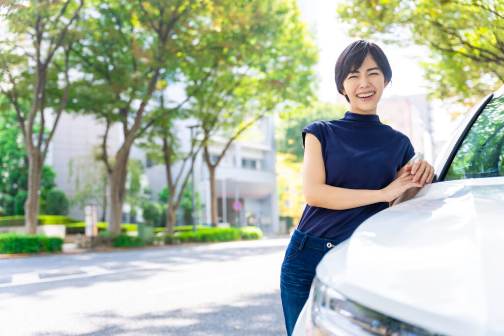 カーリースでお気に入りの車が納車されて嬉しい女性のイメージ